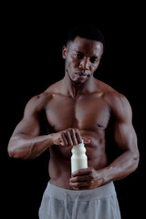 man big muscles with milk bottle over black background