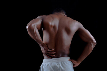 Fototapeta na wymiar Healthy young african man exercising Pain back. Bodybuilder training on a black background.