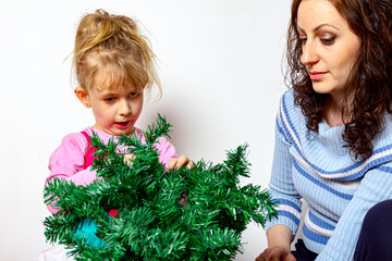 Mother with her daughter are arrange artificial Christmas tree