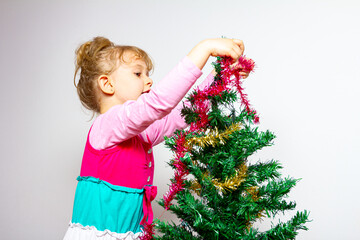 Child girl is arranging ornament decoration on artificial Christmas tree