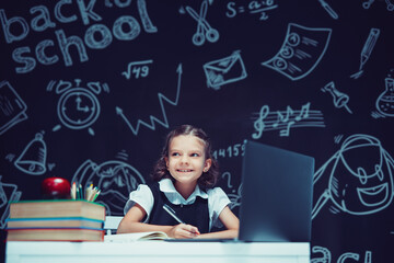 Smiling caucasian schoolgirl sitting at laptop during online lesson. Distant School Learning.