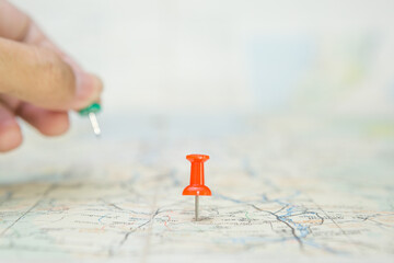 Selective focus of Red pin  and blurred hand holding a pin on map background