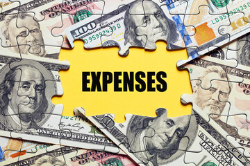 The word expenses surrounded by puzzle pieces with dollar bill money. Business finance