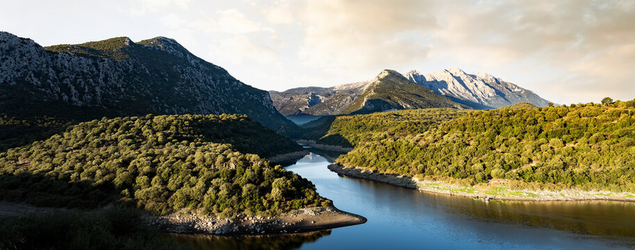 Stunning panoramic view of the Cedrino Lake (Lago del Cedrino) with the mountain range of Supramonte illuminated by a beautiful sunrise. Sardinia, Italy.