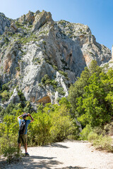 Stunning view of a tourist walking on a trail leading to Gorropu gorge. Gorropu is the most...
