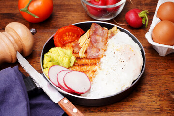 Breakfast bread with fried egg, bacon, pepper, avocado, tomato p