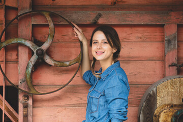 young woman near wheel of an old wooden combine harvester of XIX century