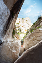 (Selective focus, focus) Stunning view of a person hiking in the Gorropu gorge during a sunny day. Gorropu is the deepest canyon in Europe located in the Supramonte area, Sardinia, Italy.