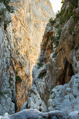Fototapeta na wymiar (Selective focus, focus) Stunning view of a person taking pictures at the Gorropu gorge during a sunny day. Gorropu is the deepest canyon in Europe located in the Supramonte area, Sardinia, Italy.