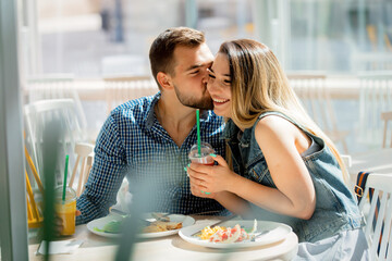 young couple sits in a cafe and have breakfast with a juice