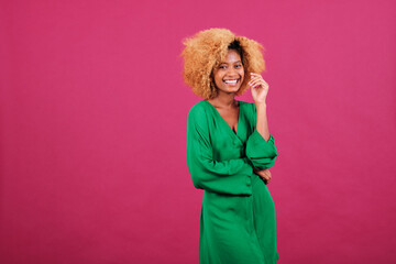 Young afro woman in stylish green dress smiling while standing over an isolated background.