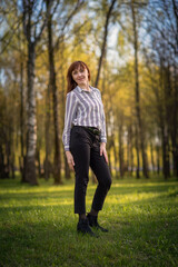 Portrait of a young beautiful girl posing in the park in full growth.
