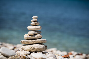 Fototapeta na wymiar Balance pyramid of stones on the sea. Small pebble pillar. A symbol of calmness and tranquility. Close-up, blurred background.