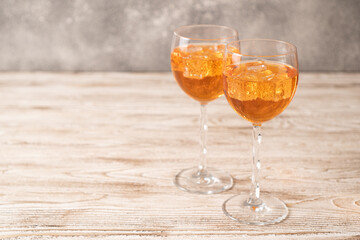 Two glasses of orange cocktails with ice on a wooden table. Aperol spritz recipe made at home.