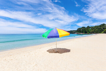 A colourful umbrella on white beach with beautiful sky.