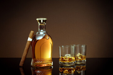 close up view of cigar, bottle of cognac and a glass aside on color back. 