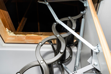 A spring tensioning mechanism that facilitates the opening of a metal ladder to the attic, as well...