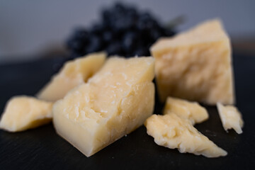 Parmesan cheese with grape on the black table. Close-up
