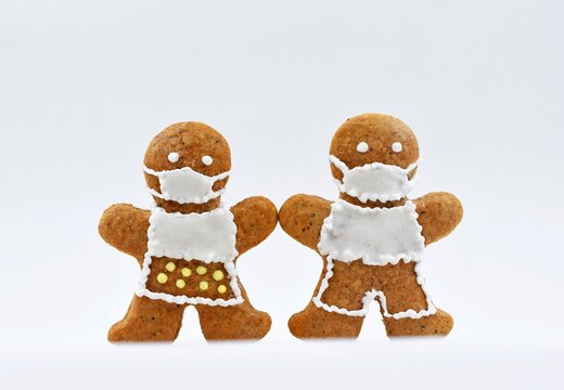 Cute gingerbread man and woman with protective face masks, white background. Creative concept in coronavirus (COVID-19) time