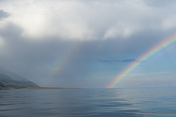 Double rainbow over the sea surface. Haze over the water. Wonderful seascape.