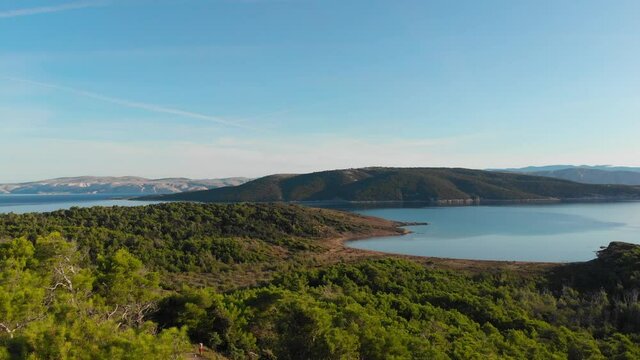 Drone footage of Croatia, Rab Island, Lopar, Sahara beach area. Early morning golden hour foreword shot of forest beach, blue Adriatic sea and mountains.