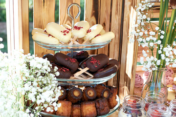 Fragment of a dessert table. cake pops in trouble and dark chocolate and cannele. Gypsophilia in the form of decoration, wooden background