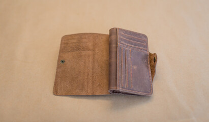 Open brown leather wallet on a beige background