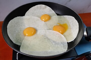 Raw Eggs on top of Tortilla Wraps inside a Frying Pan