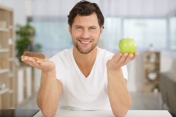 man holding chocolate donut and an apple