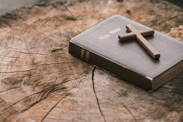 A wooden cross on Holy Bible on wooden table. Sunday readings, Bible education. spirituality and...