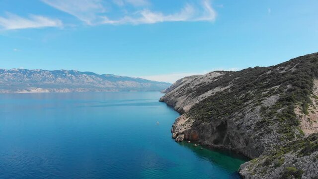 Circulating Drone footage of  small boat around Rab Island, Lopar Area in Croatia. Calm, sunny day . Epic landscape, Adriatic blue sea and mountains.