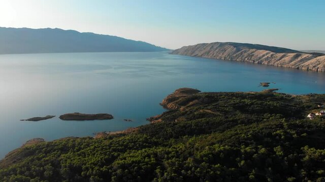 Drone footage of Rab Island, Lopar Area in Croatia. Early, calm morning after sunrise. Golden hour shoot with epic landscape, Adriatic blue sea and mountains.