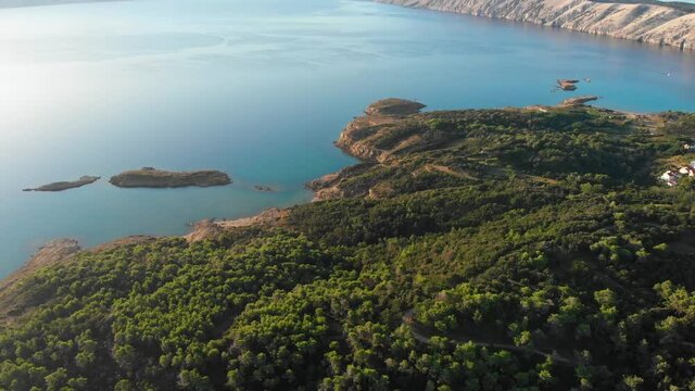 Drone footage of Rab Island, Lopar Area in Croatia. Early, calm morning after sunrise. Golden hour shoot with epic landscape, Adriatic blue sea and mountains. Holiday resort.