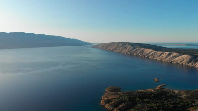 Drone footage of Rab Island, Lopar Area in Croatia. Early, calm morning after sunrise. Golden hour shoot with epic landscape, Adriatic blue sea and mountains. Small islets.