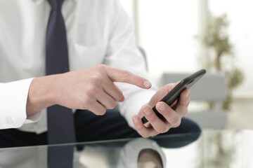 The company manager holds the phone in one hand and points to the phone screen with the other