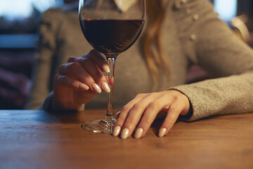 Hand of a young beautiful woman holding a glass of wine indoors of a stylish wine restaurant