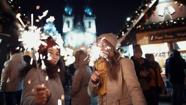 Film Shot. Prores 422. Two Young woman girlfriends laughing and dancing with sparklers in the street on christmas. new year