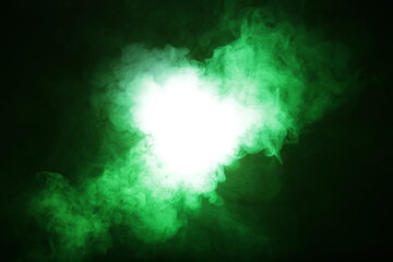 Artificial magic smoke in green light on black background