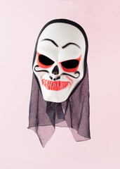 White skull face mask with bloody teeth and eyes on pink background. Minimal horror halloween concept