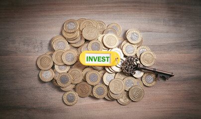 Key to Invest with a coins on the wooden background.