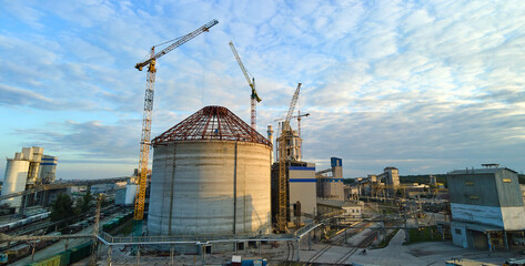 Aerial view of cement factory under construction with high concrete plant structure and tower cranes at industrial production area. Manufacture and global industry concept.