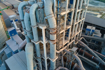 Aerial view of cement factory with high concrete plant structure and tower crane at industrial production site. Manufacture and global industry concept.