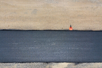 Aerial view of new road construction with newly layed black asphalt lane.