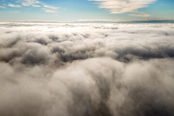 Fototapeta premium Aerial view from above of white puffy clouds in bright sunny day.
