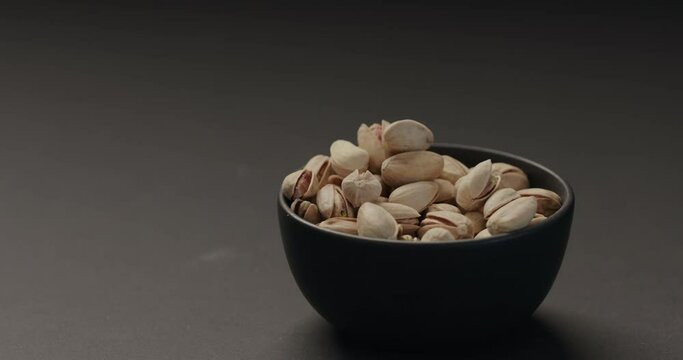 Slow Motion Man Hand Take Roasted Pistachios From Black Bowl On Black Background