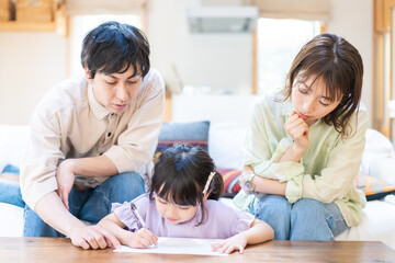 Obraz premium 家でお勉強をする女の子と両親