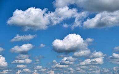 Naklejka na ściany i meble Bright landscape of white puffy cumulus clouds on blue clear sky.