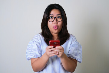 Young Asian women showing shocked face expression while holding her mobile phone