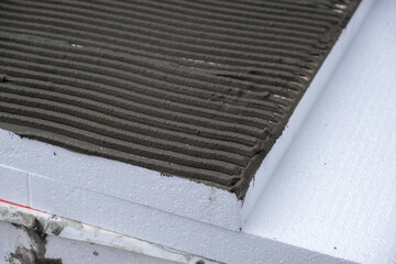 Installation of styrofoam insulation sheets on house facade wall for thermal protection.