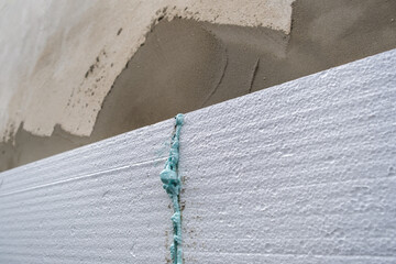 Obraz premium Installation of styrofoam insulation sheets on house facade wall for thermal protection.